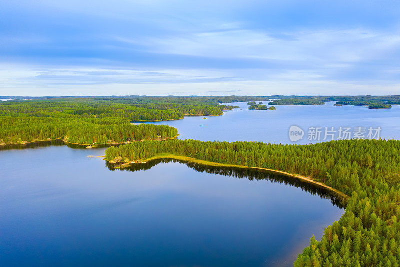 航拍的道路之间的绿色夏季森林和蓝色的湖在芬兰。Puumala Saimaa湖。